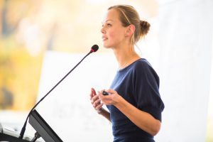 Pretty, young business woman giving a presentation in a conference/meeting setting (shallow DOF; color toned image)